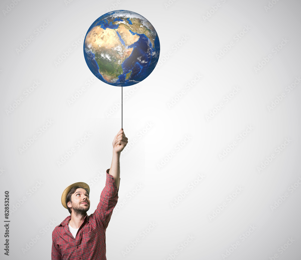 Fototapeta premium Close up of human hand holding Earth planet on rope. 