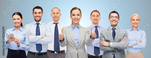 group of happy businesspeople showing thumbs up