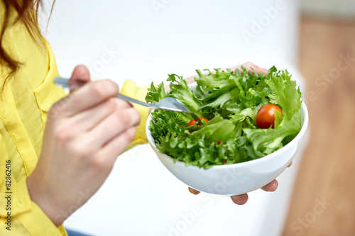 close up of young woman eating salad at home