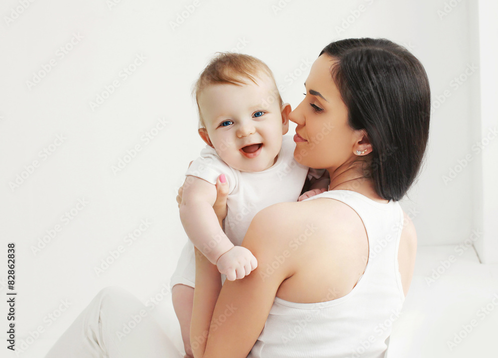 Portrait of smiling baby with mother at home in white room Portrait of smiling baby with mother at home in white room