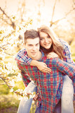 Young teen couple in the spring blossom apple trees garden