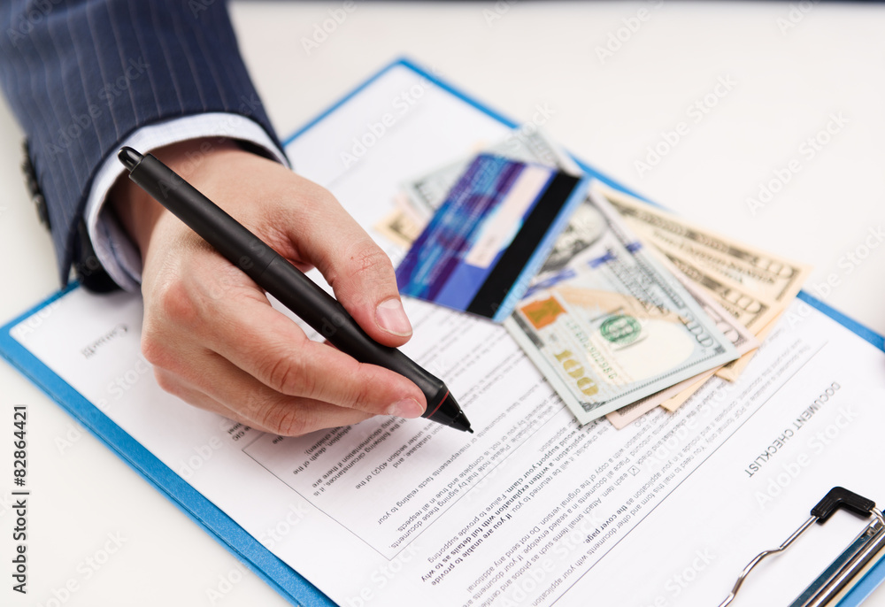Closeup of businessman hand signing document in office Closeup of businessman hand signing document in office