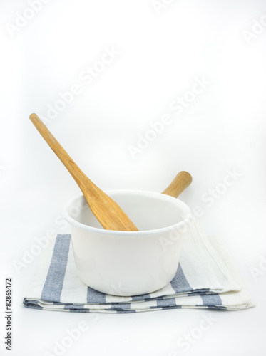 White pot and wooden spatula on a fabric