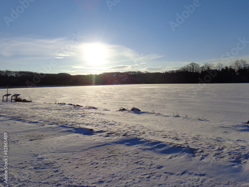 Sun going down and reflecting on a lake of frozen ice and snow.