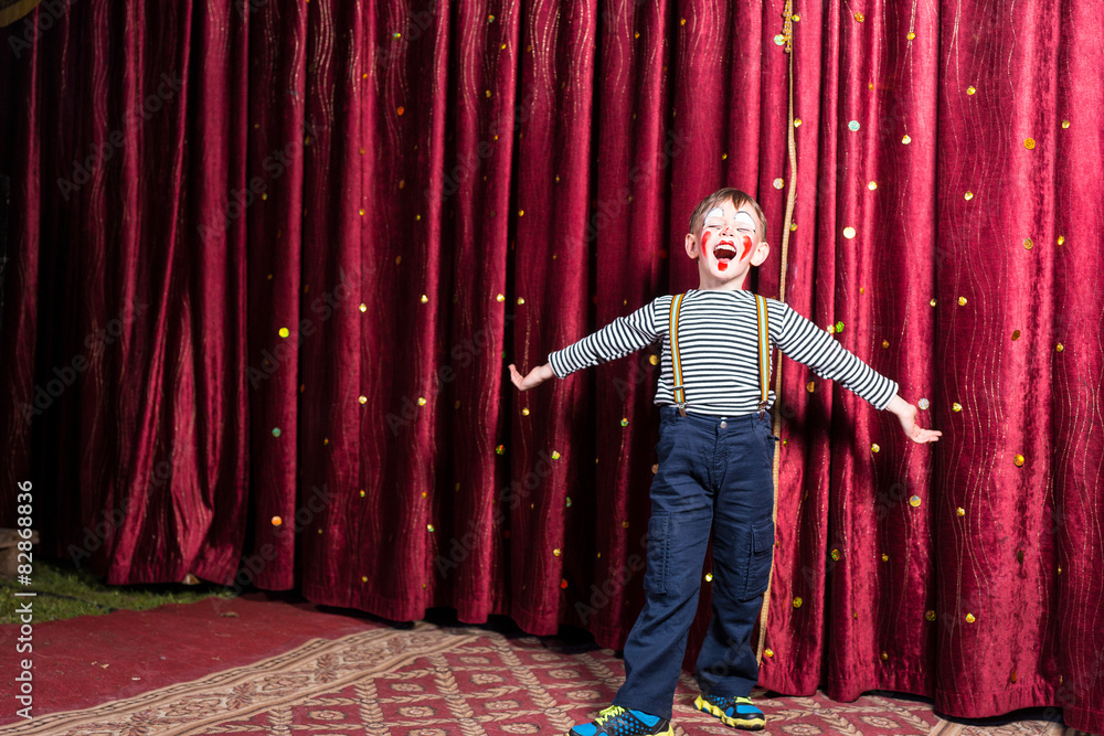 Adorable little boy singing on stage during a play