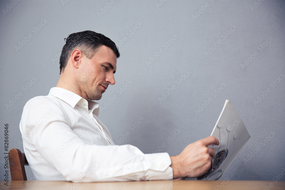 Businessman sitting at the table and reading magazine Businessman sitting at the table and reading magazine
