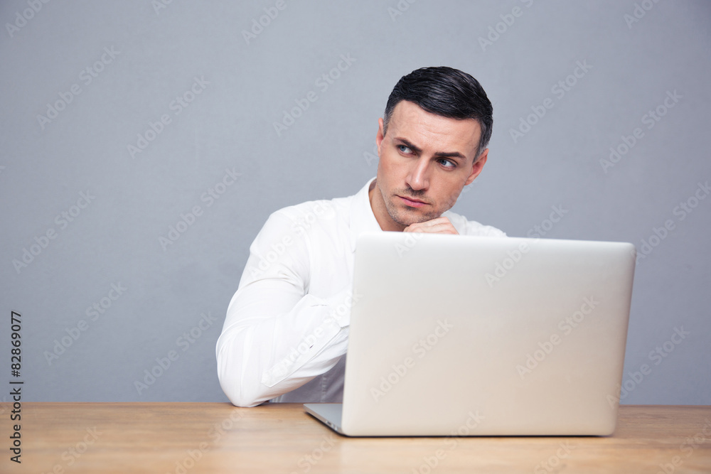Pensive businessman sitting at the table with laptop Pensive businessman sitting at the table with laptop