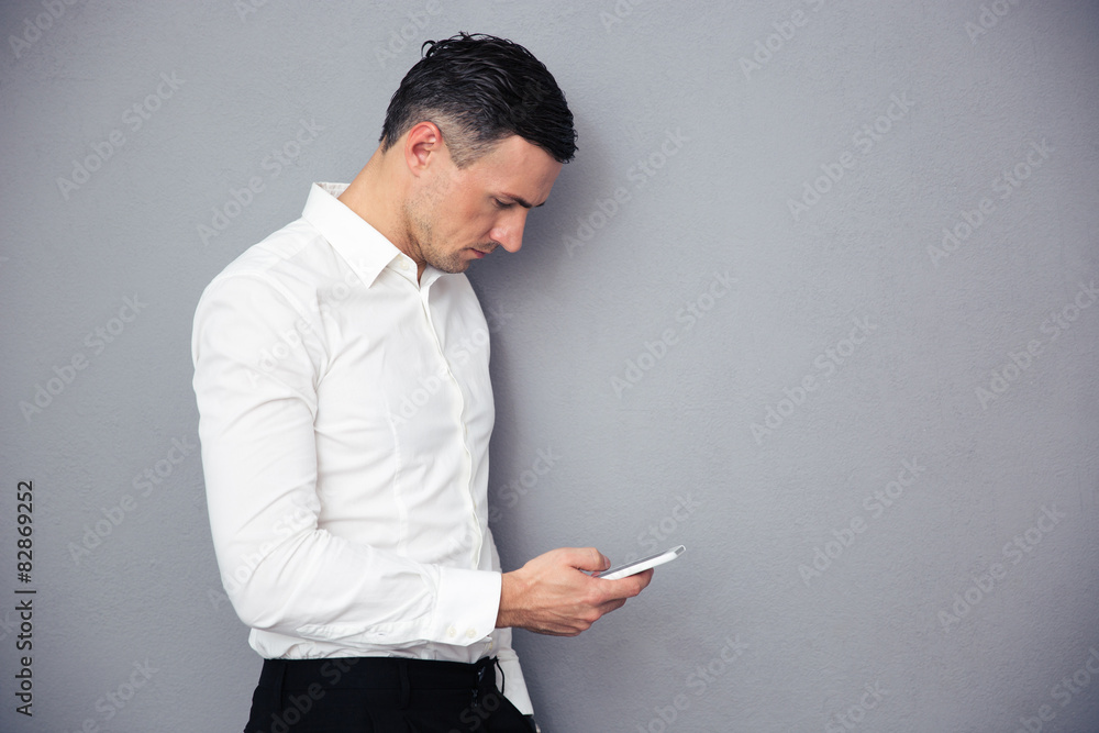 Businessman using smartphone over gray background Businessman using smartphone over gray background