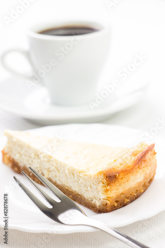 Wedge of cheesecake with dessert fork and cup of coffee