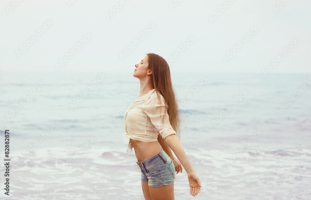 Young woman at coast enjoying fresh air sea