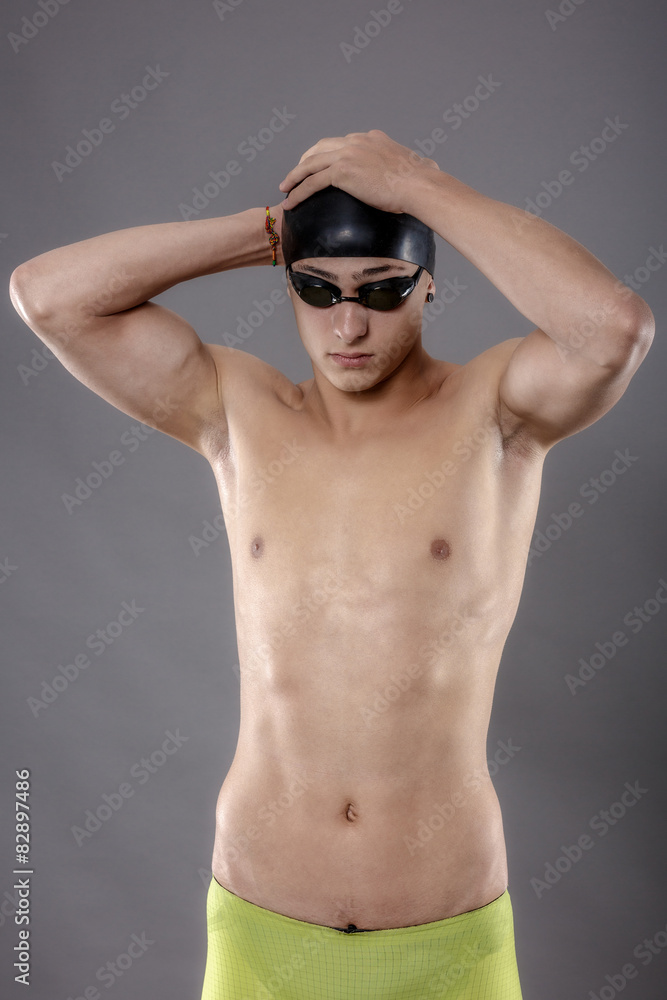 Portrait of a young man with swimming goggles on gray background Portrait of a young man with swimming goggles on gray background