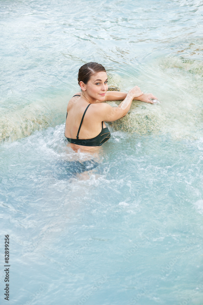 Pretty brunette woman in the natural thermal waters of spa