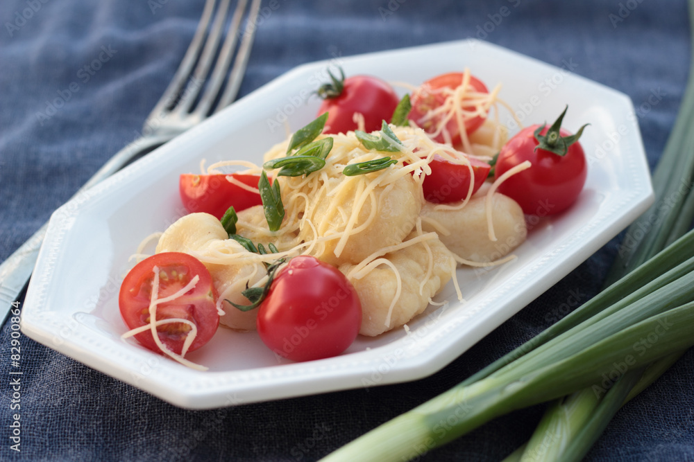 Gnocchi with tomatoes and grated cheese on a blue plate. Gnocchi with tomatoes and grated cheese on a blue plate.