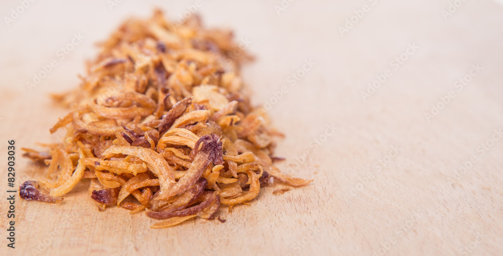 Deep fried shallots for garnishing on wooden surface Deep fried shallots for garnishing on wooden surface