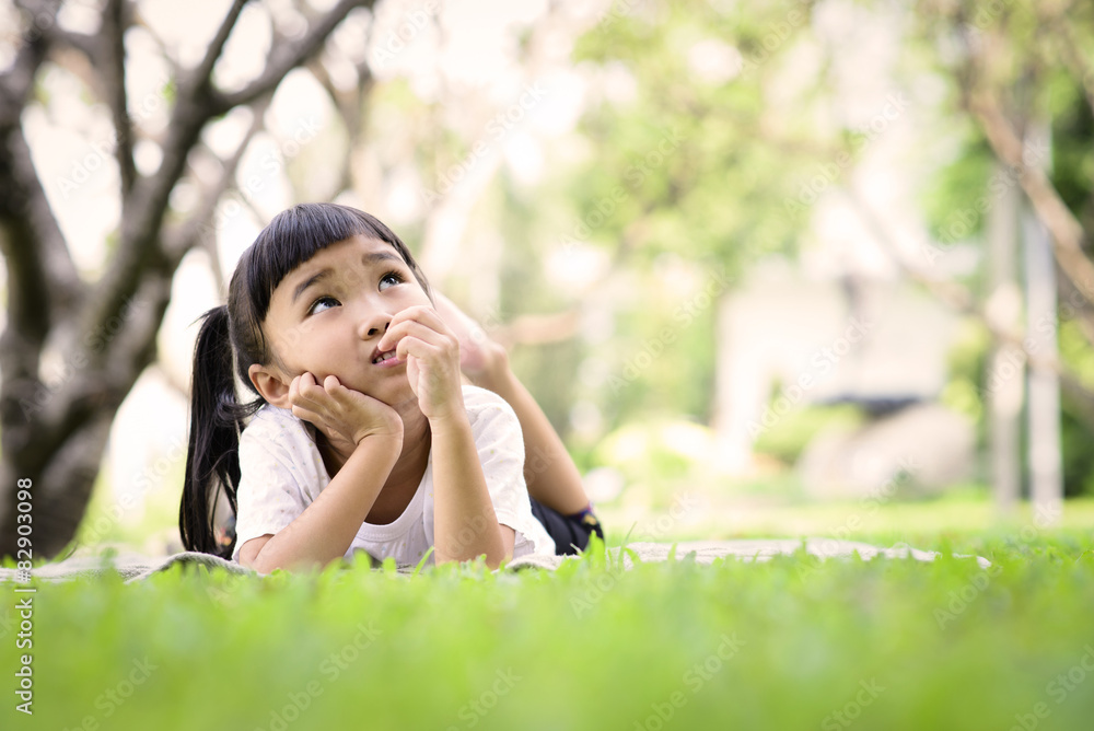 Asian kid thinking while playing in the garden