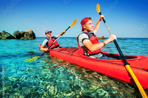 Two men paddle a kayak on the sea. Kayaking on island.