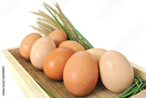 Eggs in wooden box and grass on white background