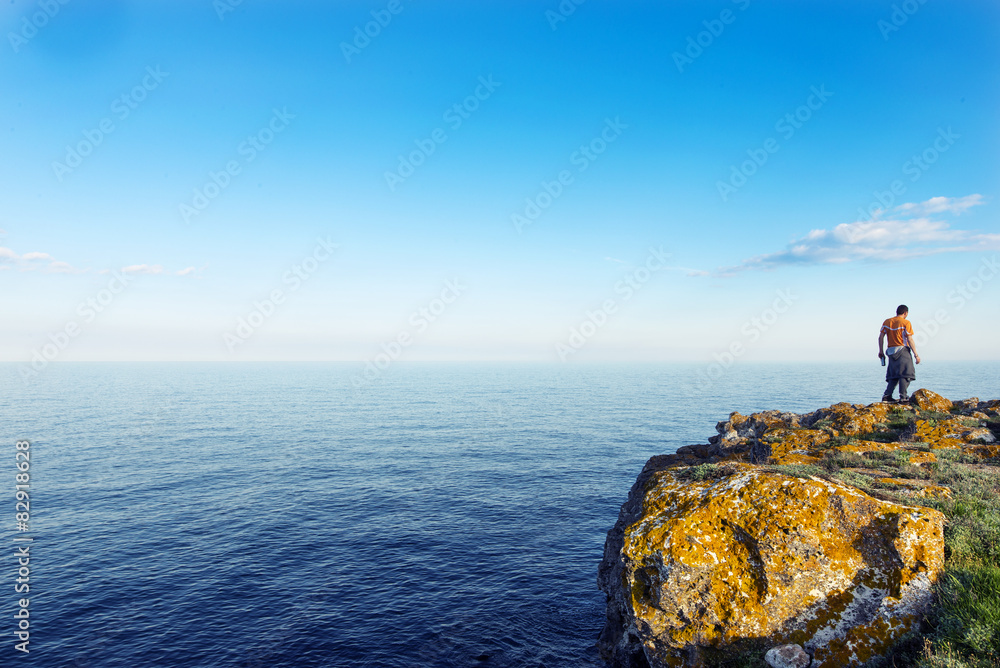 Man standing on a rock above the ocean Man standing on a rock above the ocean