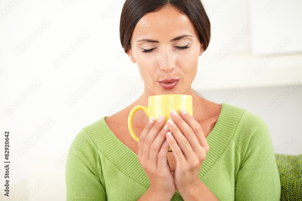 Relaxed woman blowing into a coffee cup Relaxed woman blowing into a coffee cup