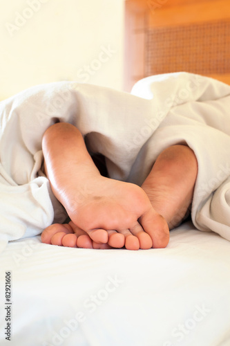 Sleeping little child funny dirty feet on white bed linen