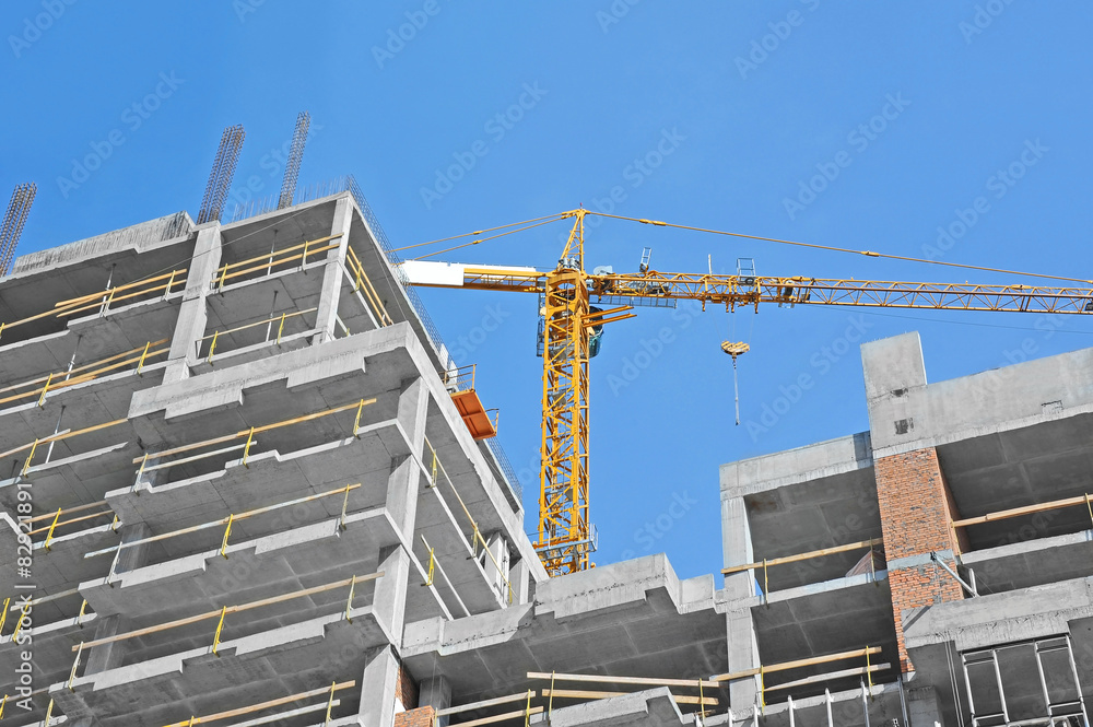 Naklejka premium Crane and building construction site against blue sky