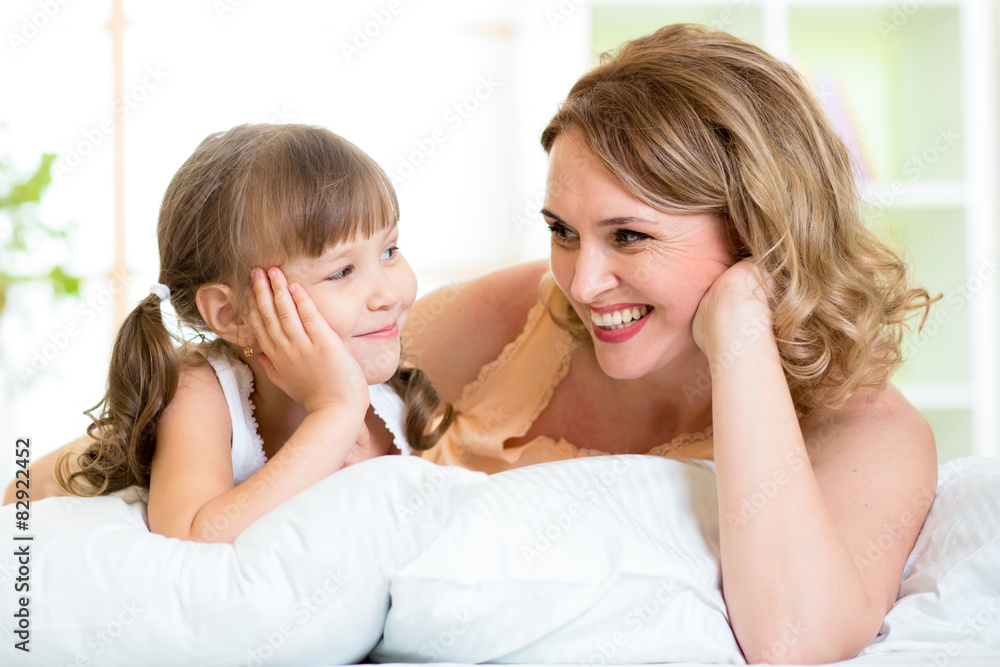 happy mom and daughter lie on bed and look each at other happy mom and daughter lie on bed and look each at other