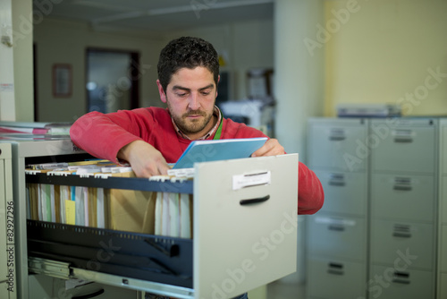 Vászonkép Office clerk searching documents and files