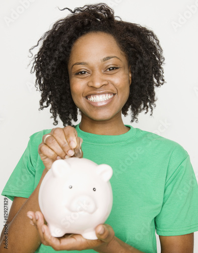 African woman putting coin in piggy bank photo