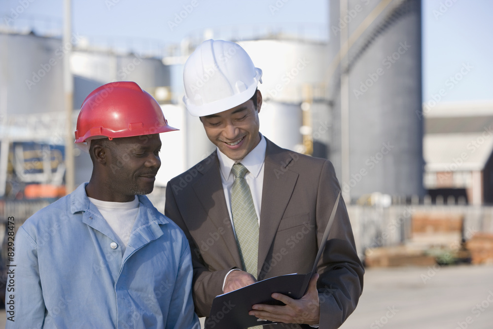Multi-ethnic businessman and construction worker looking at paperwork Multi-ethnic businessman and construction worker looking at paperwork