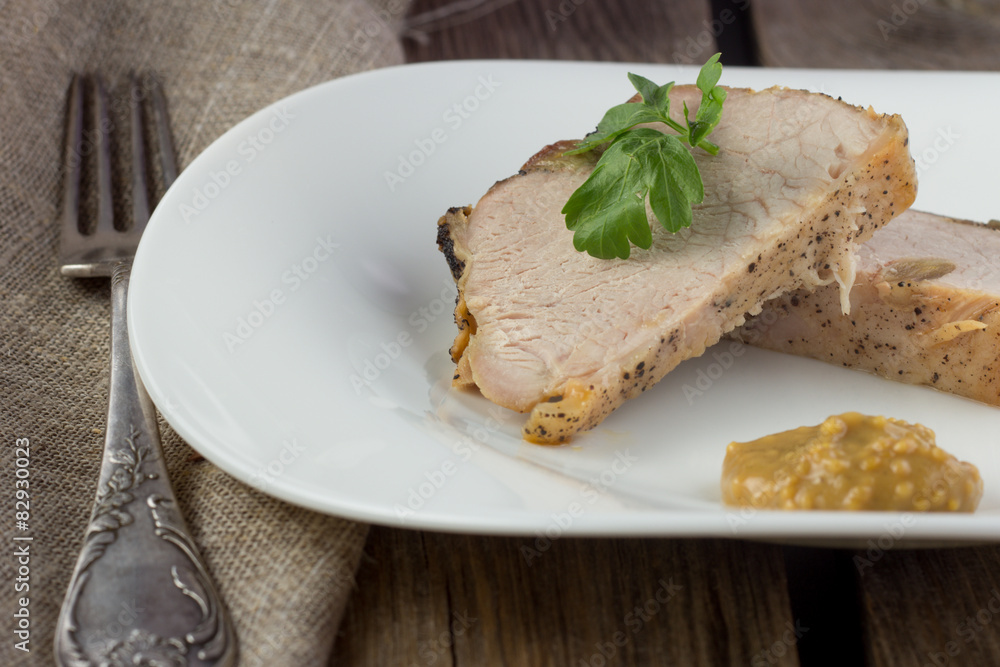 Slices of baked ham on white dish and metal fork Slices of baked ham on white dish and metal fork