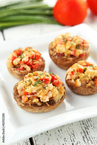 Stuffed mushrooms on plate on white wooden background
