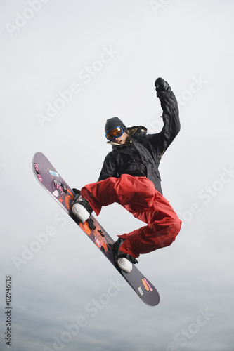 Mixed race teenager in mid-air on snowboard photo