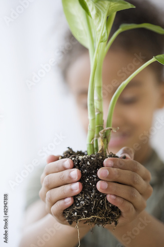 Mixed Race girl holding plant