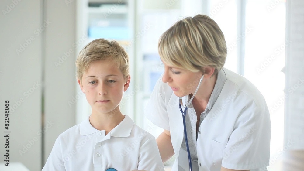 Doctor examining 12-year-old boy with stethoscope Doctor examining 12-year-old boy with stethoscope