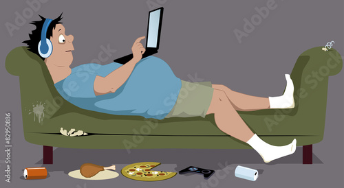 Overweight guy lying on a couch with a laptop photo