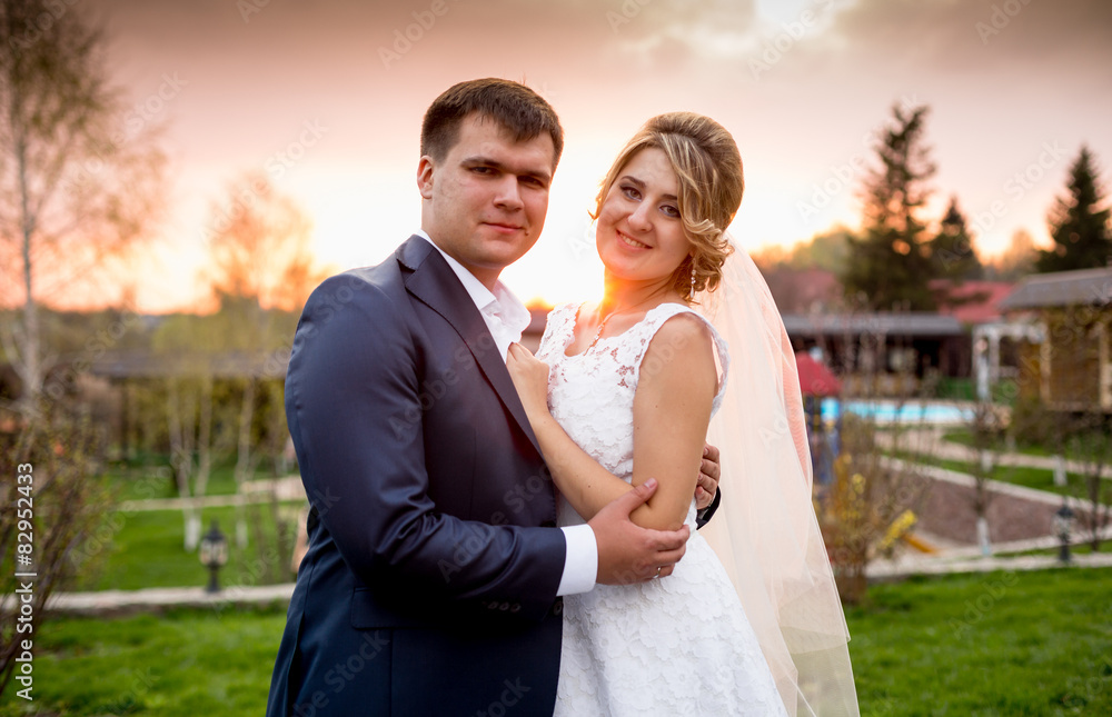 portrait of happy bride and groom hugging at sunset in park portrait of happy bride and groom hugging at sunset in park