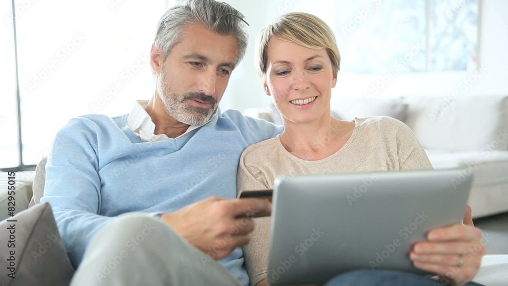 Cheerful mature couple e-shopping on internet Cheerful mature couple e-shopping on internet