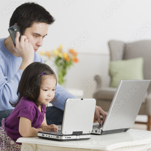 Father and daughter using laptops photo