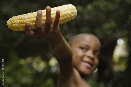 African American boy holding ear of corn photo