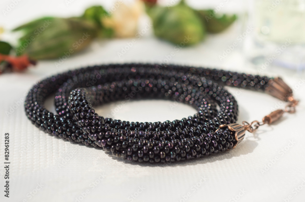 Knitted necklace from dark beads on a textile background Knitted necklace from dark beads on a textile background