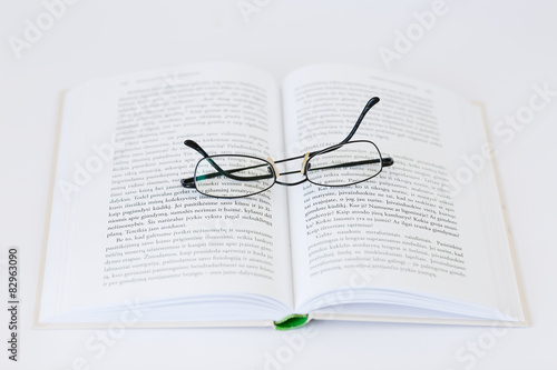 Open book with glasses on the top isolated