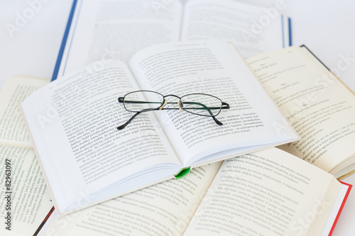 Bundle of books with glasses on the top isolated