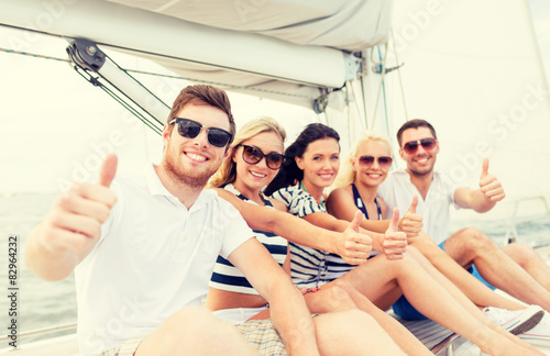 smiling friends on yacht showing thumbs up