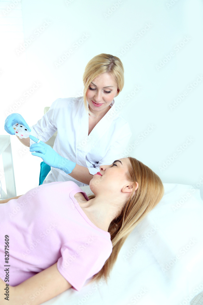 Fototapeta premium Cosmetologist applying permanent make up on lips