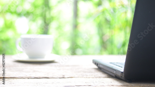 Coffee cup and laptop on wood table 