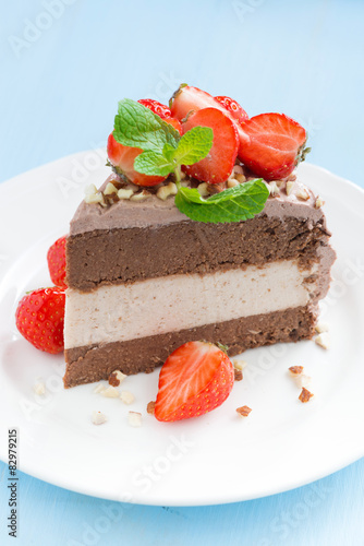 piece of chocolate cake of three layers with fresh strawberries