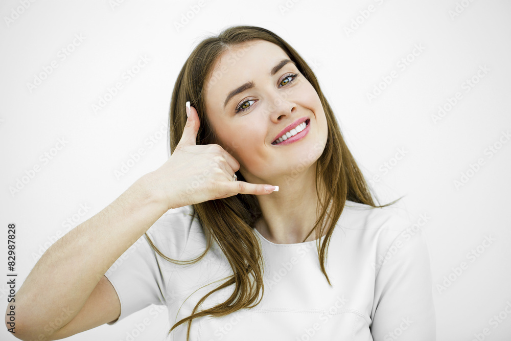 Young happy smiling brunette woman with call me gesture Young happy smiling brunette woman with call me gesture
