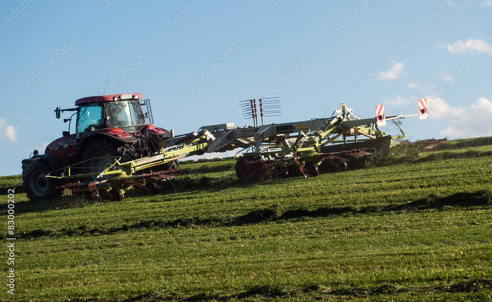 Fototapeta premium Traktor auf Wiese beim Heuwenden