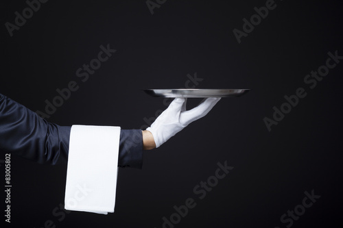 Image of a waiter hand holding a tray on dark background