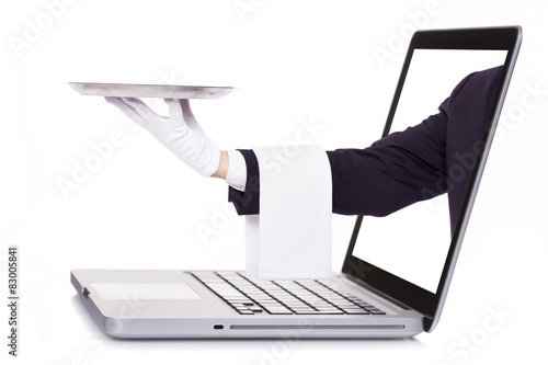 Waiter hand holding a silver tray through a laptop, isolated on photo